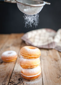 Stacked donuts with powdered sugar on wooden background
