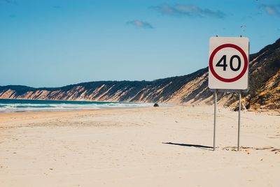 Speed limit sign at beach against sky