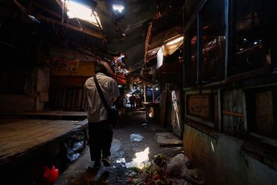 Rear view of man standing in illuminated building