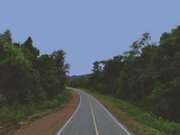 Empty road amidst trees against clear sky