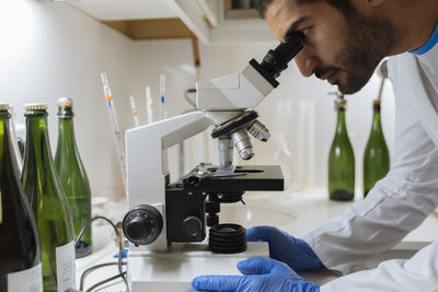 Winemaker analyzing a sample under a microscope in a winery lab.