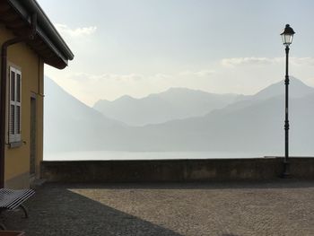 Street amidst town and mountains against sky at lake como 