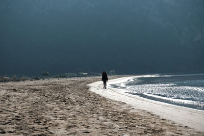 Rear view of man walking on street during winter