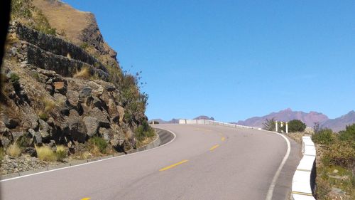 Road amidst mountains against clear blue sky