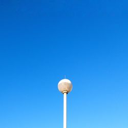 Low angle view of communications tower against clear blue sky