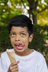 Close-up of a young boy eating ice-cream outdoors in a park.