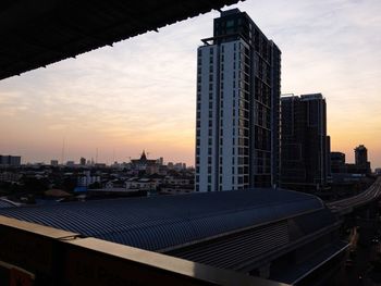 Modern buildings in city against sky during sunset