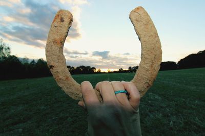 Close-up of hand holding stone against sky