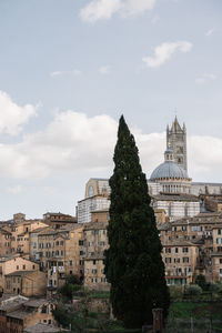 Buildings in city against cloudy sky