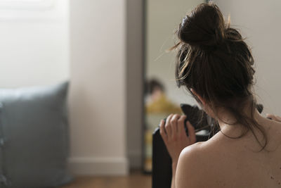 Rear view of shirtless woman at home