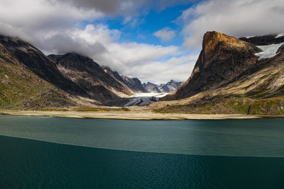 Scenic view of lake by mountains against sky