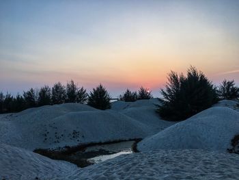 Scenic view of snow covered landscape against sky during sunset