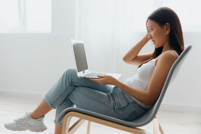 Young woman using laptop while sitting on sofa at home