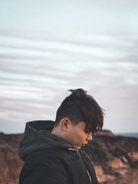 Portrait of young man standing by sea against sky