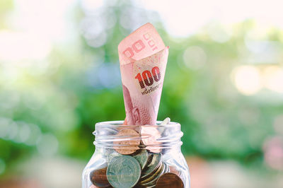Close-up of paper currency and coins in glass jar