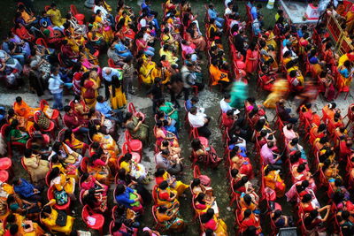 Crowd. people are sitting on a ground to see a cultural event.