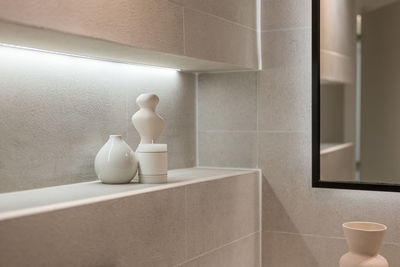 A corner of stylish bathroom with accessories. detail shot of a shelf with candle and ceramic vases. 