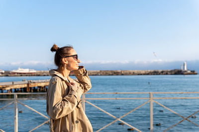 Side view of woman standing by sea against clear sky