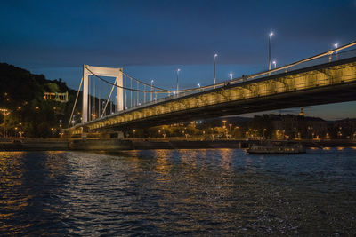 Elisabeth bridge illuminated at night with cruise boat and blue sky