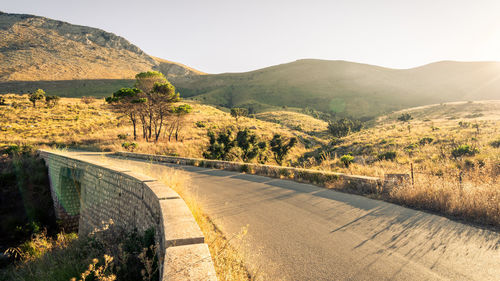 Road leading towards mountains against clear sky