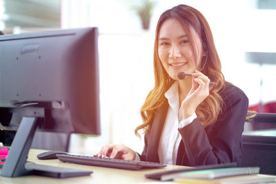 Portrait of young woman using phone while sitting on table