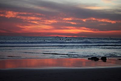 Scenic view of beach against cloudy sky during sunset