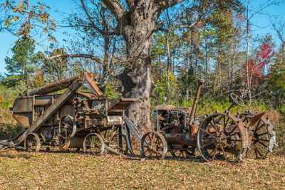 Abandoned vehicle on field against trees