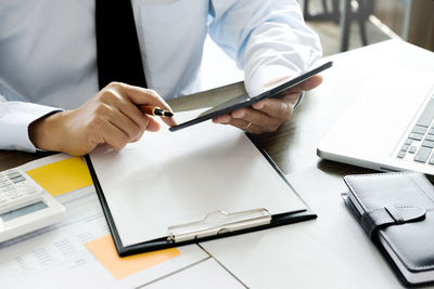 Midsection of man using mobile phone on table