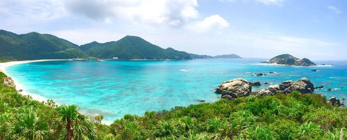 Scenic view of sea by mountains against sky