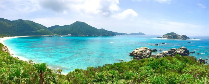 Scenic view of sea by mountains against sky