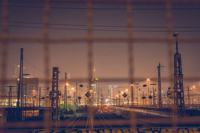 Train on track against clear sky at night seen through fence