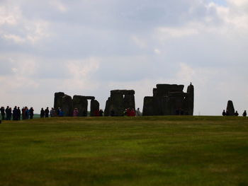 View of people on field against cloudy sky