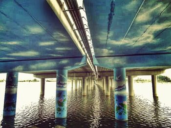 Bridge over river against cloudy sky