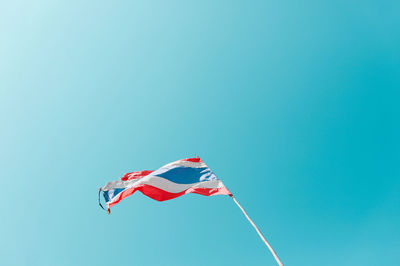 Low angle view of flag against clear blue sky