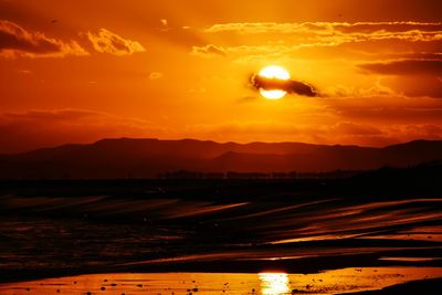 Scenic view of silhouette mountains against orange sky