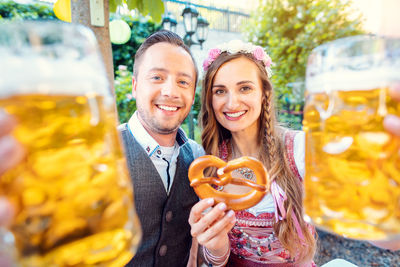Portrait of smiling couple standing outdoors with beer glass