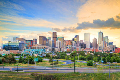 Modern buildings in city against sky during sunset