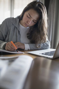 Young woman using phone while sitting on table