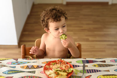 Shirtless cute girl eating food at home