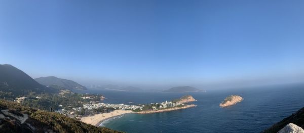 Aerial view of sea and mountains against clear blue sky