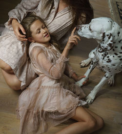 High angle view of girl, her mother and dalmatian dog lying on wooden floor