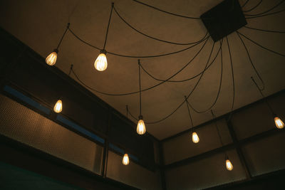 Low angle view of illuminated pendant lights hanging from ceiling