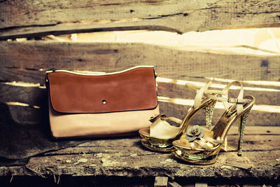 Close-up of shoes and bag by wooden wall