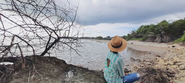 Rear view of man looking at rock against sky