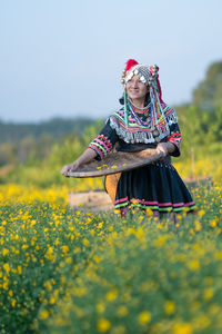 Midsection of woman with yellow flowers on field