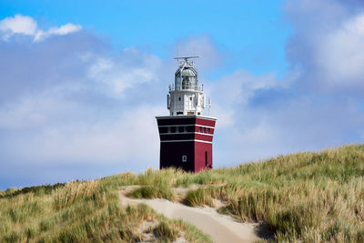 Lighthouse on field against sky