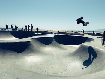 People jumping on skateboard against sky