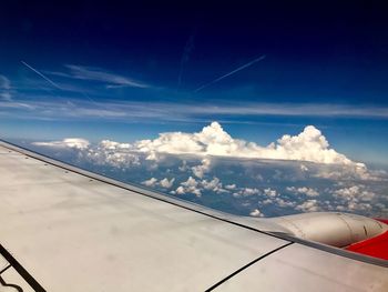 Airplane wing over clouds against blue sky