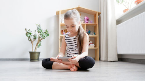 Young woman using phone while sitting on floor at home