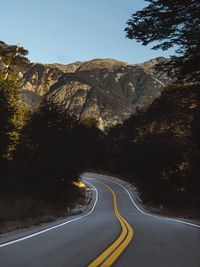 Country road by mountain against sky